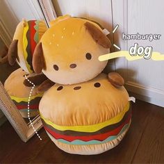 a stuffed dog sitting on top of a hamburger shaped pillow in front of a mirror