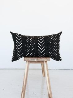 a black and white pillow sitting on top of a wooden stool