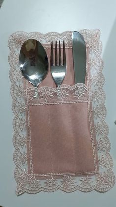 the utensils are placed on top of the pink napkin with lace around it