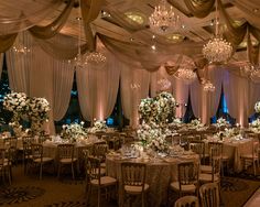 a banquet hall decorated with white flowers and chandeliers