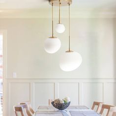 a dining room table with four lights hanging from it