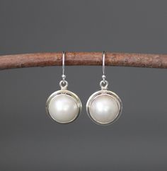 "Gorgeous round white freshwater pearls are bezel set in simple Bali Silver charms.  These dangle from silver earwires.   Choose from balled silver earwires (as shown and sent with stoppers for the ends of the wires) or plain leverback earwires (these close in the back).  These elegant earrings are perfect for any occasion!   Pearl bezels: 11mm Bali Silver charms: 13x16mm (including the silver ring) Total length of earrings: just over 1\" Length is approximate. All silver is sterling. As the own Classic Round Pearl Drop Earrings, Pearl White Round Sterling Silver Pearl Earrings, Pearl White Sterling Silver Round Pearl Earrings, Everyday White Round Pearl Earrings, Nickel Free Classic Dangle Pearl Earrings, Classic Nickel-free Dangle Pearl Earrings, Classic Pearl Earrings Nickel Free, Classic Sterling Silver Pearl Pendant Earrings, Round Pearl Pendant Earrings For Anniversary