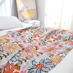 an unmade bed with colorful flowers on it