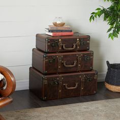 three suitcases stacked on top of each other in front of a chair and potted plant