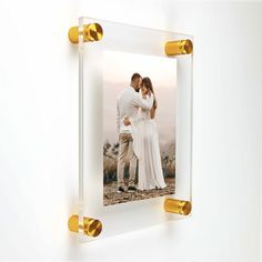 a couple standing next to each other in front of a white wall with gold accents