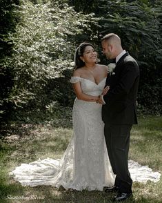 a bride and groom standing together in the grass