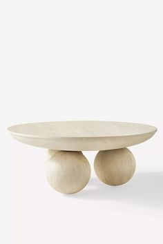 a white table with two wooden balls on it's legs and one is sitting in front of the table