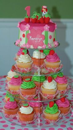 cupcakes are stacked on top of each other in front of a pink and green cake