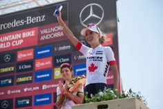 the woman is holding up her medal on the podium