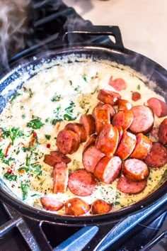 a skillet filled with cooked sausages and gravy on top of the stove