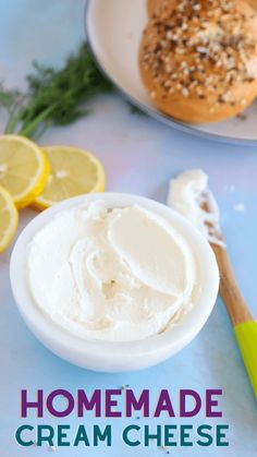 homemade cream cheese is in a bowl next to lemons and bread on a plate