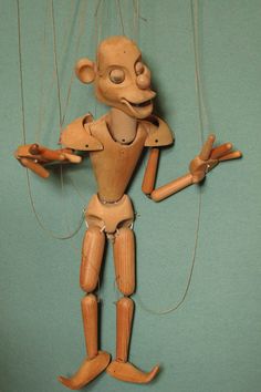 a wooden toy with strings attached to it's body and arms, holding two hands in the air