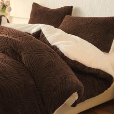 a bed covered in brown and white comforters