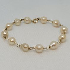 Lovely 12kt yellow twisted gold link bracelet with twelve 8.5mm cream-white freshwater pearls. The freshwater pearls have a lustrous clean nacre. The bracelet is 7.75 inches long, secured with a spring ring clasp, and weighs 10.6 grams.  Rock N Gold Creations is located in San Diego, California, serving customers locally, nationally, and internationally for over 30 years. Pre-owned jewelry and watches are evaluated before they are listed. The founder is a GIA graduate; the company adheres to GIA standards. Rock N Gold Creations has won many jewelry design competitions and has a passion for providing quality custom jewelry, fine estate jewelry, and fine watches. Classic Gold Bracelet With Pearl Drop, Gold Akoya Pearl Round Bracelet, Gold Akoya Pearl Bracelet, Classic Gold Pearl Drop Bracelet, Yellow Gold Pearl Bracelets With Pearl Drop, Formal Gold Bracelet With Pearl Drop, Formal Yellow Gold Pearl Bracelet With Pearl Chain, Formal Yellow Gold Pearl Chain Bracelet, Classic Gold Pearl Bracelet Hypoallergenic