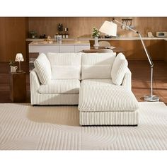 a white couch sitting on top of a wooden floor next to a lamp and table