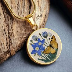 a yellow butterfly sitting on top of a blue and white flowered vase pendant necklace