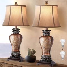 two lamps sitting on top of a wooden table next to a lamp with a brown shade