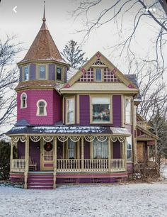 a purple victorian style house with a turret and two stories on the second story is covered in snow