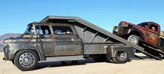 an old pick up truck with a flat bed attached to it's trailer in the desert