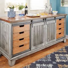 an old wooden buffet table with drawers and bottles on top in a blue dining room