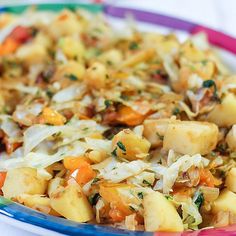 a plate full of potatoes and carrots on a white tablecloth with pink rim