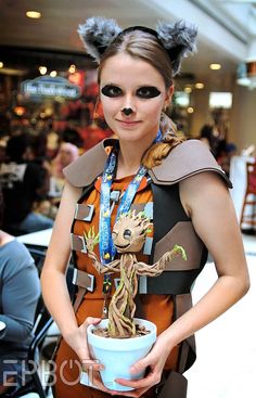 a woman in costume holding a potted plant with her face painted like a baby groote