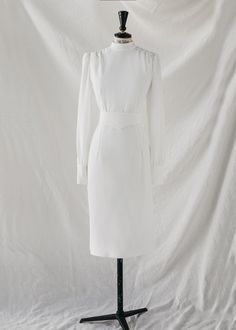 Wedding dress made UPON REQUEST (*) from the Ready to Love collection.



Wedding dress made to order.

midi cut

Long sleeves with closed cuffs and buttons.

Neck to the box.

Straight skirt.


Back with invisible zip and covered button placket. 

Belted framed waist.

Made in white crepe.












Size

US

UK



Bust

(cm)*






Waist

(cm)*






Hip

(cm)*






Back 

(cm)*














XS

34-36

6-8

84

64

90

35






S

36-38

8-10

88

68

94

39






m

38-40

10-12

92 

72

98

43






L

40-42

12-14

96

76

102

47






XL

42-44

14-16

100

80

106

51
















 *GENERAL MEASUREMENTS: some fabrics are more flexible than others. Please keep this in mind when measuring yourself.

To keep your CHERUBINA dress like the first day, we recommend a professional To Love, Simple Wedding Dress, Dry Cleaners, Straight Skirt, Wedding Dresses Simple, Simple Weddings, Simple Wedding, Bridal Collection, Intimate Wedding