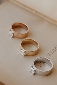 three wedding rings sitting on top of an open book