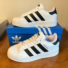 The Classic Adidas Superstar Sneaker In All White With Black 3-Stripes, Black Heel Tab With White Trefoil Logo, And Black Superstar On Sides. Lace Closure, Shell Toe, Sturdy And Comfortable. The Xlg Has A Slightly Elevated Midsole. Cute Sneaker! Nwt Mint Condition, Comes In Original Adidas Box. Sold Out On Line. Qt8f4x5d4a4tt Coffee Shoes, Superstar Adidas, Black Superstar, Classic Adidas, Adidas Shoes Women, Adidas Original, Cute Sneakers, Black Heel, Adidas White