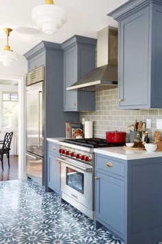 a kitchen with blue cabinets and white counter tops, an oven and stove top in the center