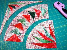 a pair of scissors sitting on top of a cutting board next to some pieces of fabric