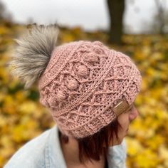 a woman wearing a pink knitted hat with pom - pom on top