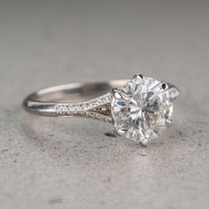 a white gold ring with a round cut diamond in the center and pave set shoulders