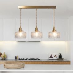 three lights hanging over a kitchen counter top