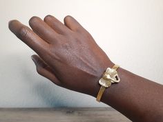 If you want to make a bold statement about your love for our magnificent elephants, our African elephant head bracelet will help you do that. This beautiful Elephant bracelet is handmade in the Kenya by skilled artisans. The elephant bracelet pendant is made from matte gold plated brass with an open and adjustable band. Show off your unique style with our handmade elephant head bracelet. Here's more information about this gorgeous elephant bracelet Handmade in Kenya using vintage tooling Hollow Adjustable Matte Gold Brass Bracelets, Matte Gold Adjustable Bangle Jewelry, Adjustable Hand Cast Yellow Gold Jewelry, Adjustable Hand-cast Yellow Gold Jewelry, Matte Gold Brass Bracelets As Gift, Adjustable Gold Hand-cast Bracelet, Adjustable Hand Cast Gold Bracelet, Beautiful Elephant, Handmade Elephant