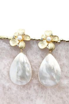 These statement bridal earrings will turn heads as you walk down the aisle. Featuring mother of pearl teardrop earrings with a gold flower stud base. Classic and modern wedding jewelry for brides, bridesmaids, and mother of brides. Wear these pearl teardrop wedding earrings for your rehearsal dinner, bridal shower, and your wedding for a touch of timeless elegance. Shop all your bridal jewelry needs at shopkateandmari.com. Chic Teardrop Pearl Earrings For Party, Chic Silver Teardrop Pearl Earrings, Teardrop Pearl Earrings For Party, Glamorous Teardrop Pearl Earrings, Glamorous Teardrop Pearl Earrings For Pierced Ears, Chic White Teardrop Pearl Earrings, Chic Teardrop Pearl Earrings For Pierced Ears, Teardrop Mother Of Pearl Wedding Earrings, Modern Wedding Jewelry