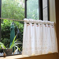 a window with a curtain and potted plant in it next to the window sill