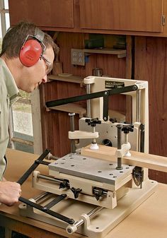 a man wearing headphones is working on a machine in a woodworking shop while looking at it