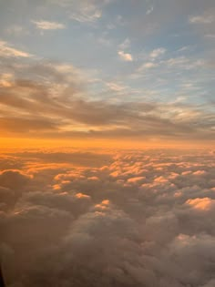 the view from an airplane looking down on clouds and sky at sunset or sunrise,