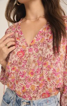 Add a dose of bright florals to your wardrobe with the Carine Lima Floral Top from Z Supply. This flowy, v-neck top features a vibrant floral print that will instantly refresh your look. The 3/4 blouson sleeves + ruffle collar detail add a touch of femininity + elegance, making it a standout piece. The tie detail at the neckline offers versatility + a playful finish. Crafted from lightweight fabric, this top is perfect for both work + play. Pair it with your favorite denim for a casual outing or Feminine V-neck Top For Spring, Icon Jewelry, Flower Branding, Hair Socks, Bright Florals, Flower Tops, Cactus Flower, Ruffle Collar, Ladies Boutique