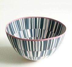 a blue and white striped bowl sitting on top of a table next to a wall