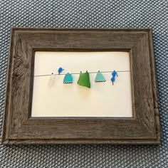 three little birds are hanging on a line with clothes pins in the shadow box frame