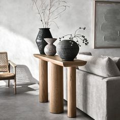 three vases are sitting on a table in front of a couch with a chair