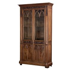 a wooden china cabinet with glass doors and carvings on the front, in an antique style