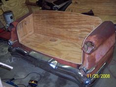 an old car is being worked on in a garage with wood planks and plywood