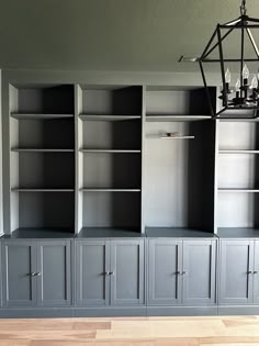 an empty room with several gray bookcases and a chandelier