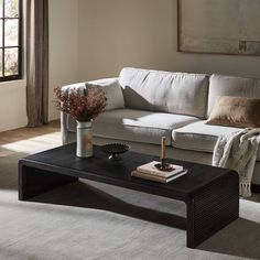 a living room with a couch, coffee table and vases on the end tables