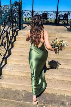 a woman in a green dress walking up some steps