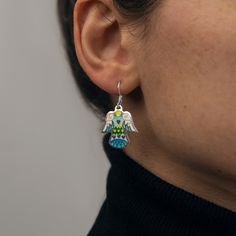 Introducing our Handcrafted Love Angel Earrings, the perfect embodiment of divine elegance, ideal for gifting that special someone or treating yourself to a touch of heavenly charm. These earrings are meticulously crafted with sterling silver and adorned with the vibrant allure of Cloisonné Enamel. The unique technique used in their creation breathes life into the design, making each pair truly unique. A testament to high-quality craftsmanship, the earrings are made from 925 sterling silver, ensuring durability and long-lasting shine. Key Features: - Handmade Love Angel Earrings - Compact size, measuring just 0.8 inches (2cm) long - Crafted from premium 925 Sterling Silver - Adorned with radiant Cloisonné Enamel - Arrives in a beautiful, branded gift box These earrings don't just make a st Elegant Sterling Silver Jewelry With Artistic Design, Enamel Drop Earrings As A Gift, Enamel Drop Earrings For Gifts, Enamel Ear Wire Jewelry, Symbolic Drop Earrings Jewelry Gift, Symbolic Drop Earrings Jewelry As Gift, Artisan Enamel Jewelry With Ear Wire, Symbolic Drop Earrings As A Gift, Enamel Jewelry For Pierced Ears As A Gift