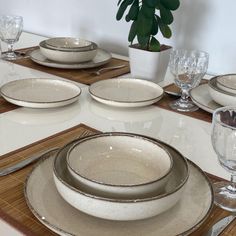 the table is set with white dishes and place settings